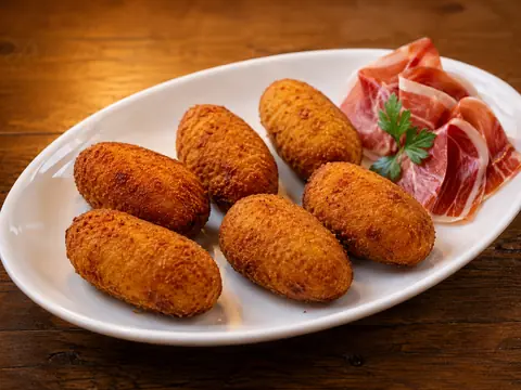 Croquetas de jamón acompañadas de jamón serrano