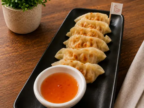 Cinco gyozas de pato acompañadas de salsa