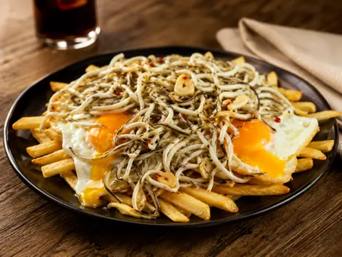 Huevos rotos con gulas sobre patatas fritas
